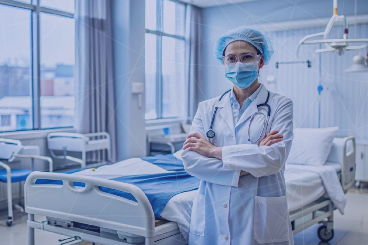 Healthcare worker in a hospital environment with a patient bed and medical equipment